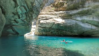 a river tracer swims in a deep azure pool surrounded by marble walls